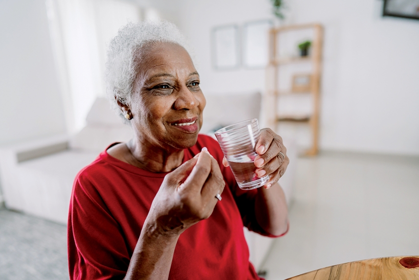 A woman in a red blouse prepares to take her medication.