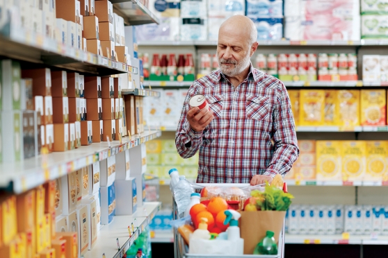 A man examines the nutrition facts on a can in the grocery store.